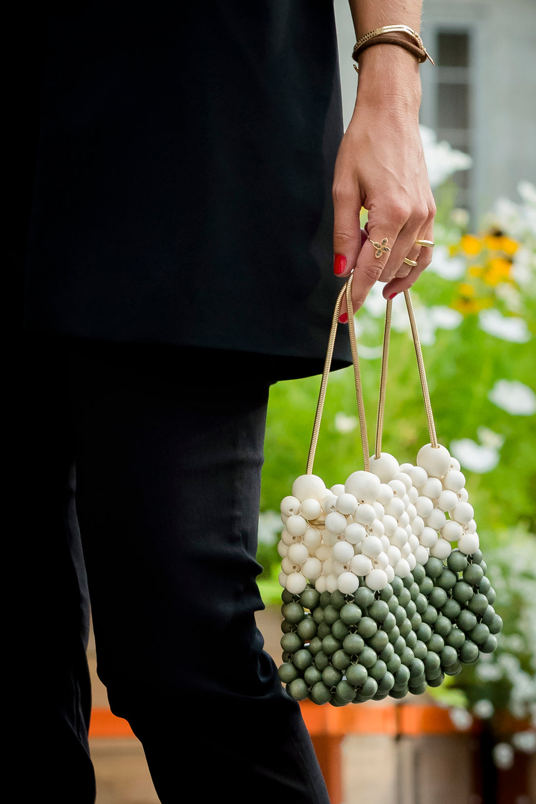Woman carrying Moy studio white and green wooden woven beads handbag lilo bag