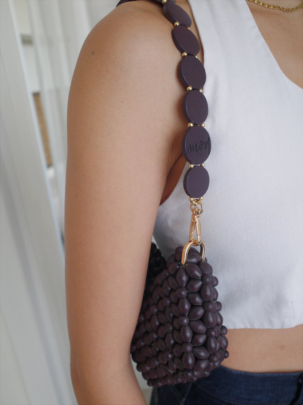 Person holding a dark brown beaded handbag with a gold clasp.